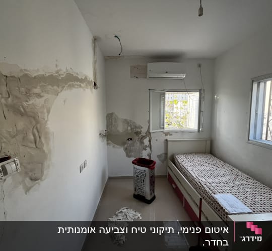 חדר עם קירות מתוקנים, מיטה וכלי עבודה לצביעה